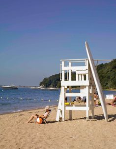 a lifeguard tower on the beach with people lounging around