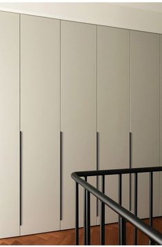 an empty room with white cupboards and black railing on the wooden floor next to it