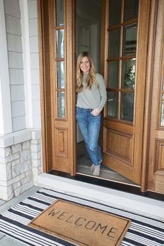 a woman standing in front of a door with her hands on her hips and smiling