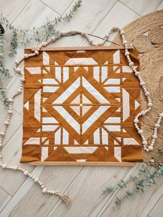 an orange and white quilt on the floor with beaded garlands next to it