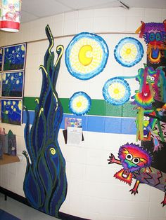 an art project is displayed on the wall in this classroom setting with colorful paper cut outs