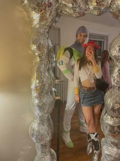 a man and woman standing in front of a mirror with disco balls on the wall