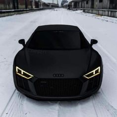 the front end of a black sports car in the snow