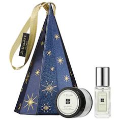 a bottle of cologne next to a blue cone shaped bag with gold stars on it