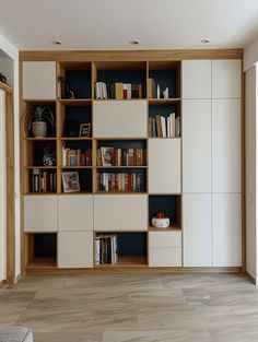 a book shelf filled with lots of books on top of a hard wood floor next to a window