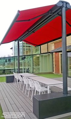 an outdoor dining area with tables and chairs under a red awning on the deck