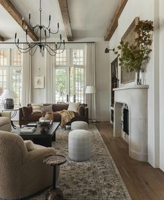 a living room filled with lots of furniture and a chandelier hanging from the ceiling