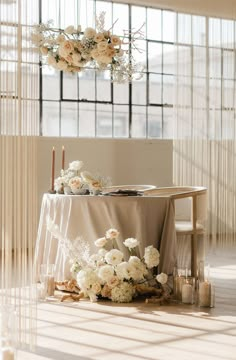 a table with flowers and candles on it in the middle of a room filled with sheer curtains