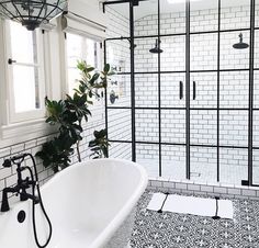 a white bath tub sitting next to a black and white tiled shower stall in a bathroom