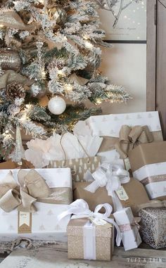 a christmas tree with presents under it in front of a white and gold holiday tree