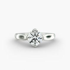 a white gold engagement ring with a round brilliant cut diamond in the center, on a plain surface