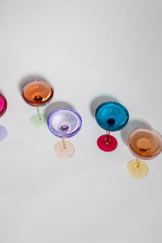 five wine glasses with different colored liquids in them