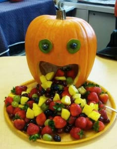 a plate with fruit on it and a pumpkin shaped like a face made out of strawberries