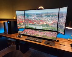 a computer desk with two monitors and keyboard on it, in front of a view of the city