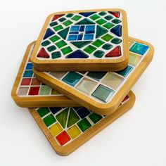 three wooden coasters with multicolored glass tiles on them, stacked on top of each other