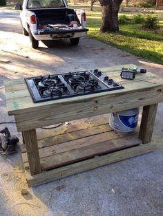 a table made out of pallet wood with a stove top on it and tools