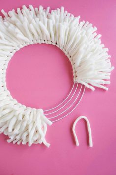 the white yarn is being used to make a wreath with two hooks and one pair of scissors