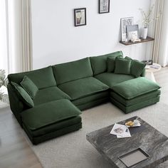 a living room with a large green couch and coffee table in front of the window