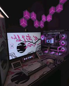 a computer desk topped with a monitor and keyboard next to a neon pink wallpaper