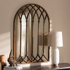 a mirror sitting on top of a table next to a lamp and a book shelf