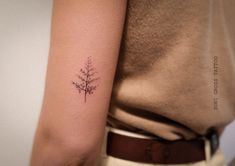 a woman's arm with a small tree tattoo on the left side of her arm