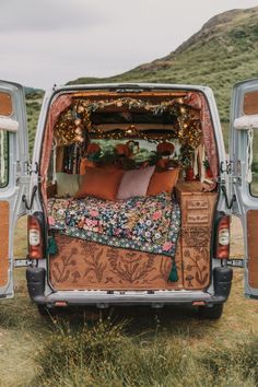 the back end of an old van decorated with pillows and blankets