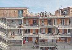 people are standing on the balconies of an apartment building with multiple floors and balconies