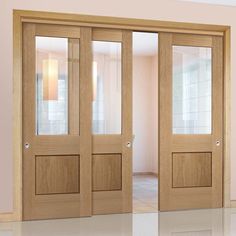 an empty room with wooden doors and glass panels on the door, in front of a pink wall