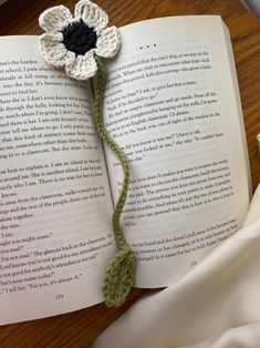 an open book with a crocheted flower on it