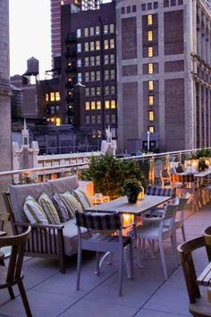 an outdoor dining area on the roof of a building with city buildings in the background