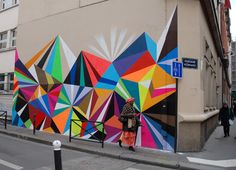 a woman walking past a colorful wall on the side of a building