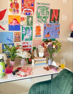 a white desk topped with lots of pictures and flowers next to a green velvet chair