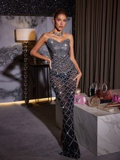 a woman in a silver dress standing next to a table