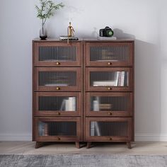 a wooden cabinet with glass doors and shelves on the top, in front of a white wall