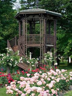 a wooden gazebo surrounded by flowers and trees