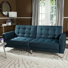 a blue couch sitting on top of a white rug in a living room next to a window