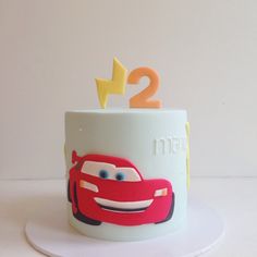 the birthday cake is decorated with cars and lightning bolt