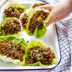 a person holding up some lettuce leaves filled with ground beef and carrots