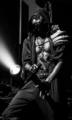 a black and white photo of a man in costume holding a microphone with his right hand