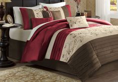 the bed is made with red and brown comforter sets, along with matching pillows