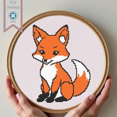 a cross stitch fox sitting in front of a white wall