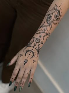 a woman's hand with tattoos on her left arm and the sun and moon