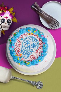 a decorated cake sitting on top of a white plate next to a knife and fork