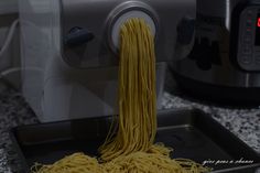 spaghetti being cooked in front of an electric pressure cooker on a granite countertop