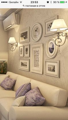 a living room filled with white furniture and pictures on the wall above it's couch