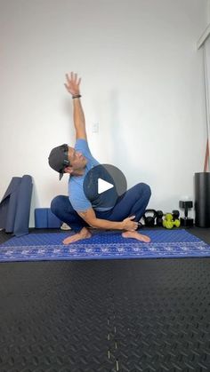 a man is doing yoga on a mat with his hands in the air while stretching