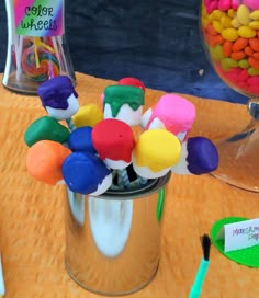 there are many colorful candies in a bucket on the table next to each other