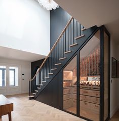 a staircase leading up to a kitchen in a modern style home with wood floors and white walls