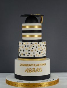 a three tiered cake with black and white stripes, gold stars and graduation cap on top