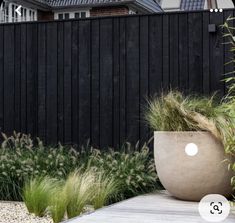 a large planter sitting on top of a wooden deck next to a tall black fence